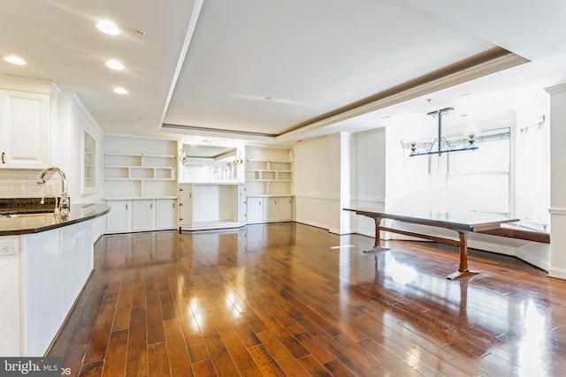 kitchen with white cabinets, dark hardwood / wood-style floors, a raised ceiling, and sink