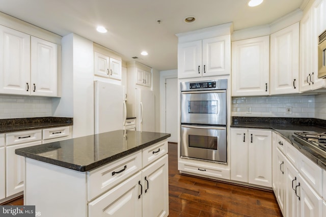 kitchen with decorative backsplash, white cabinetry, dark wood-type flooring, and appliances with stainless steel finishes