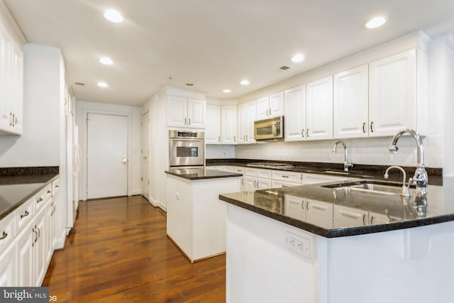 kitchen with a center island, white cabinets, sink, dark hardwood / wood-style flooring, and stainless steel appliances