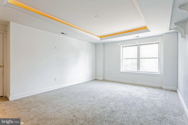 unfurnished room featuring a tray ceiling, light colored carpet, and ornamental molding