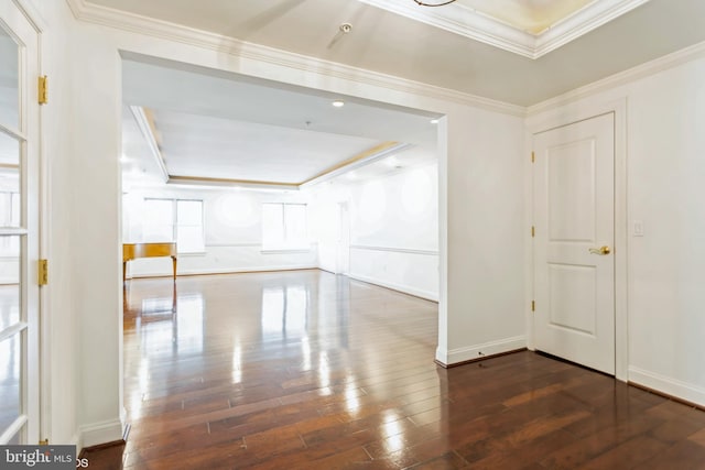 unfurnished room with a raised ceiling, crown molding, and dark wood-type flooring