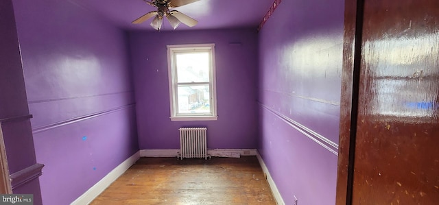 unfurnished room with hardwood / wood-style flooring, radiator heating unit, and ceiling fan