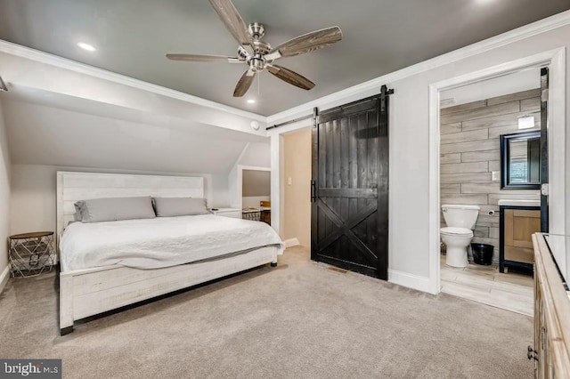 bedroom featuring a barn door, light colored carpet, ceiling fan, and connected bathroom