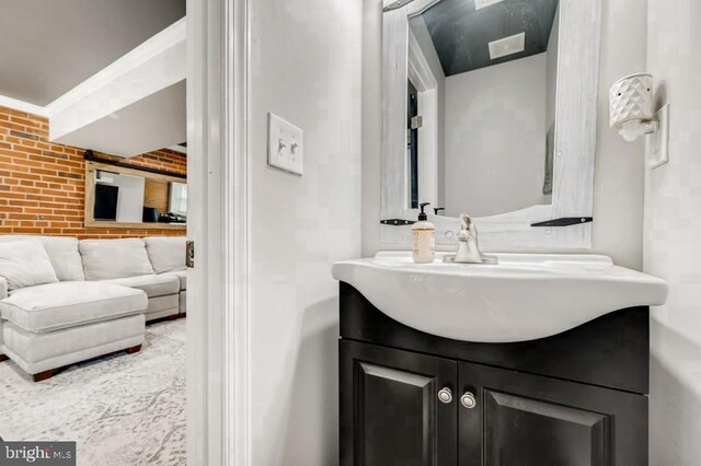 bathroom with vanity and brick wall