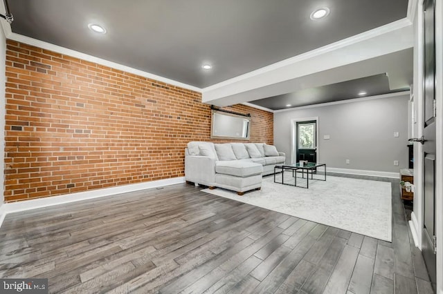 unfurnished living room featuring wood-type flooring, crown molding, and brick wall