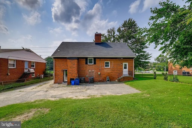 rear view of property with a lawn and cooling unit