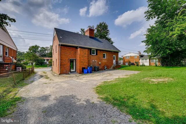 back of property with a lawn and central AC