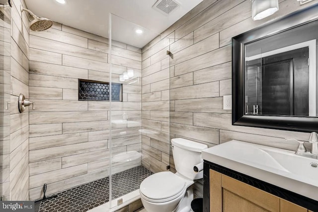 bathroom featuring an enclosed shower, vanity, toilet, and tile walls