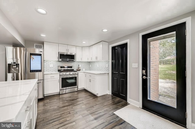 kitchen with white cabinets, appliances with stainless steel finishes, and dark hardwood / wood-style flooring