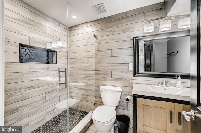 bathroom featuring vanity, a shower with shower door, tile walls, and toilet