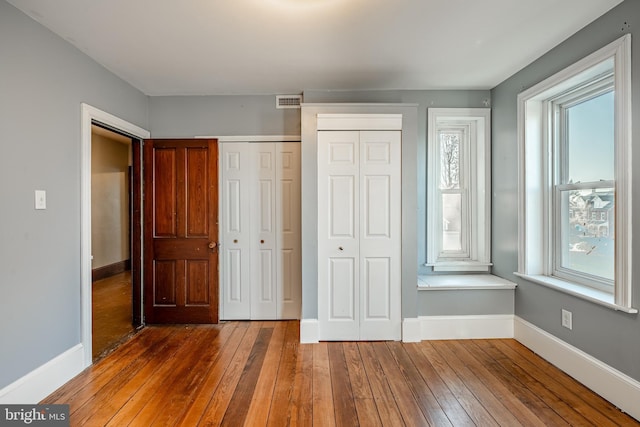 unfurnished bedroom featuring two closets and dark wood-type flooring