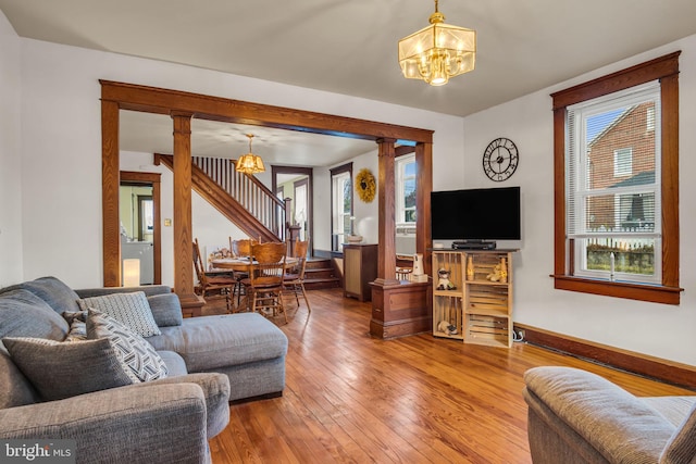 living room with ornate columns, wood-type flooring, and a chandelier