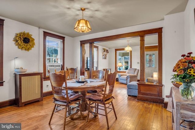 dining space featuring light wood-type flooring, an inviting chandelier, and cooling unit