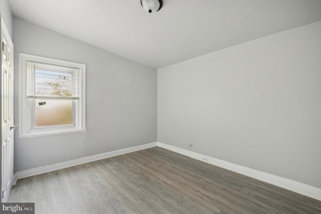 empty room with hardwood / wood-style floors and vaulted ceiling