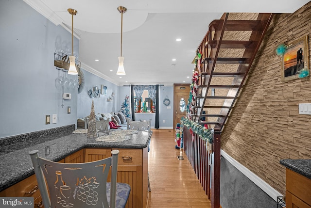 kitchen featuring kitchen peninsula, crown molding, dark stone countertops, light hardwood / wood-style floors, and decorative light fixtures