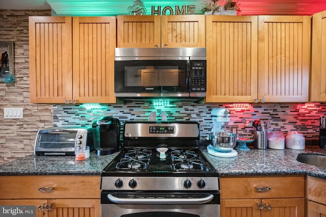 kitchen with dark stone countertops, stainless steel appliances, and tasteful backsplash