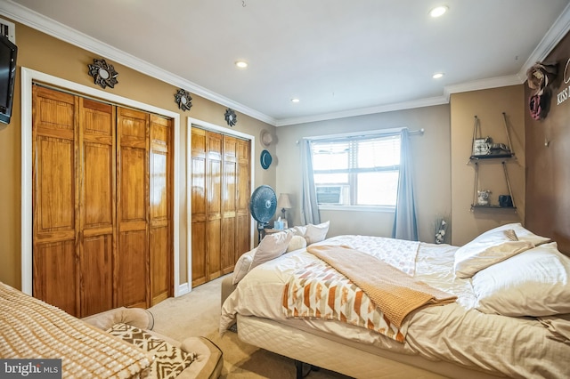 bedroom featuring light carpet, two closets, and ornamental molding