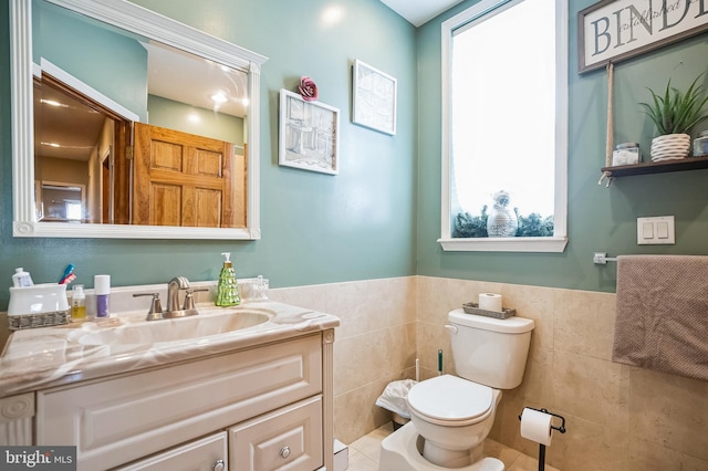 bathroom featuring tile patterned flooring, vanity, toilet, and tile walls