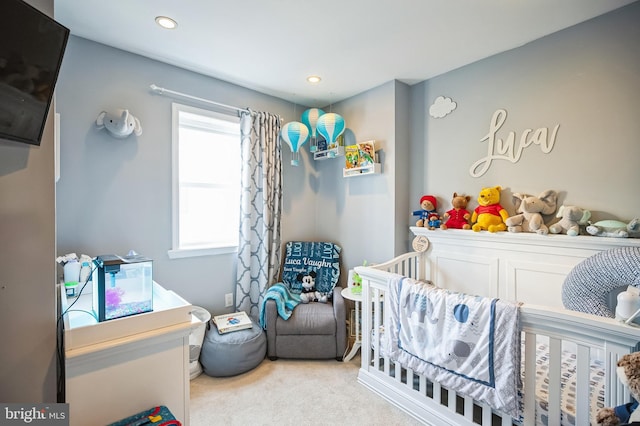 carpeted bedroom featuring a nursery area