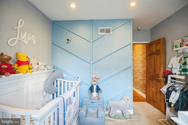 bedroom with light carpet and a nursery area