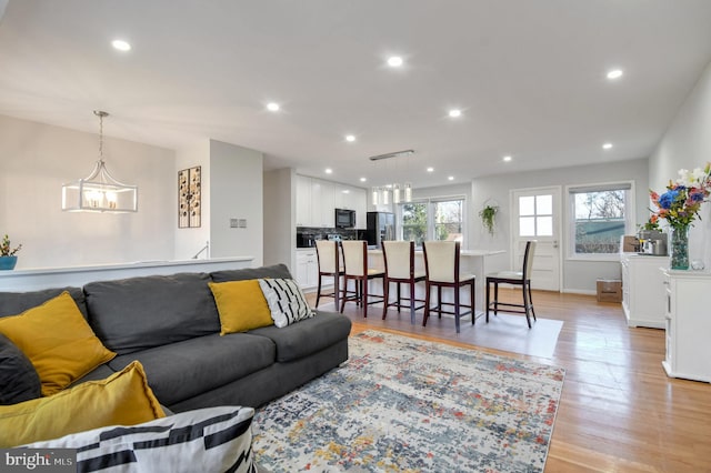 living room featuring a chandelier and light wood-type flooring