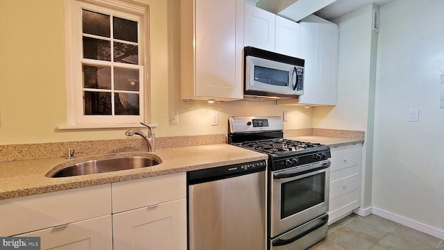 kitchen with light tile patterned flooring, appliances with stainless steel finishes, white cabinetry, and sink