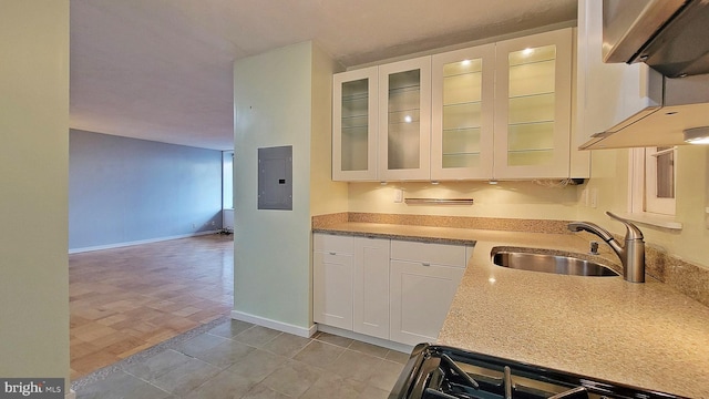 kitchen with electric panel, white cabinets, sink, light wood-type flooring, and range