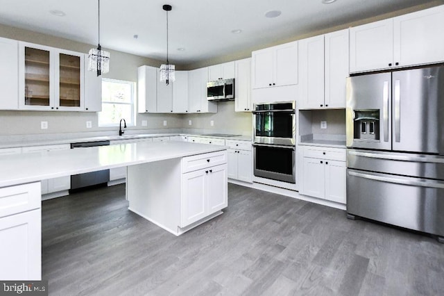 kitchen featuring white cabinetry, hanging light fixtures, and appliances with stainless steel finishes