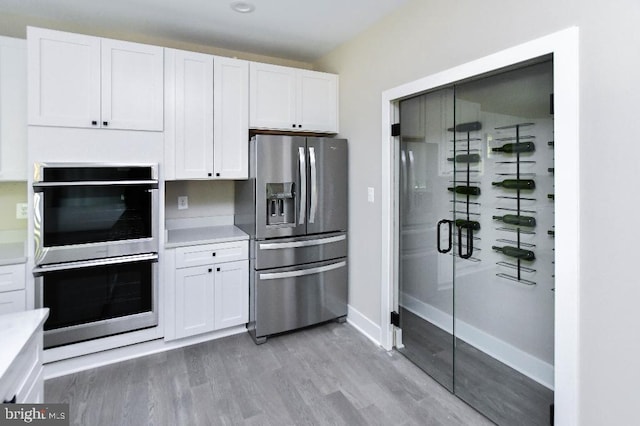 kitchen with light wood-type flooring, stainless steel appliances, and white cabinetry