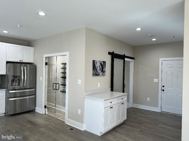 kitchen featuring a barn door, dark hardwood / wood-style flooring, white cabinetry, and stainless steel refrigerator with ice dispenser