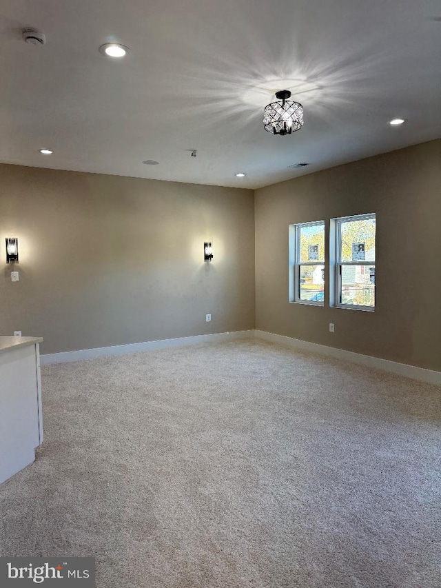 carpeted spare room with a chandelier