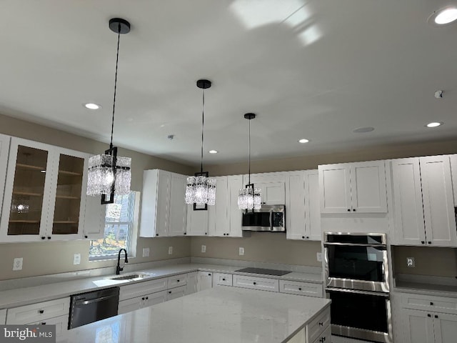 kitchen featuring light stone counters, stainless steel appliances, sink, white cabinetry, and hanging light fixtures