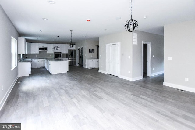 kitchen featuring a kitchen island, wall oven, refrigerator with ice dispenser, decorative light fixtures, and white cabinets