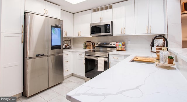 kitchen featuring white cabinets, stainless steel appliances, light stone countertops, and sink