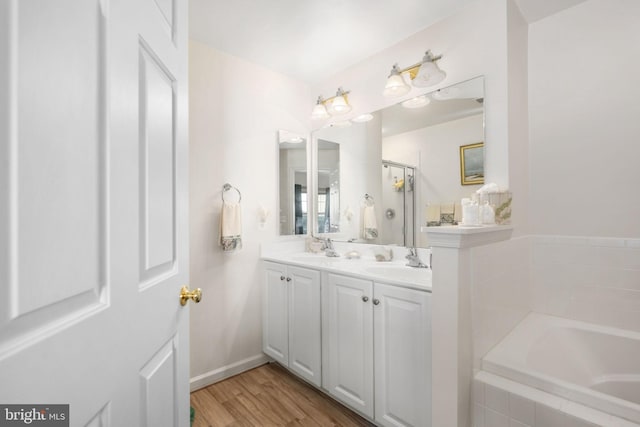 bathroom featuring wood-type flooring, vanity, and tiled bath