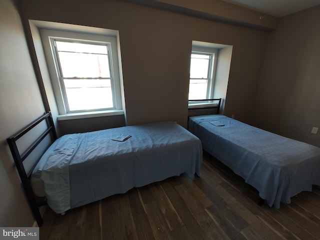 bedroom with dark hardwood / wood-style flooring and multiple windows