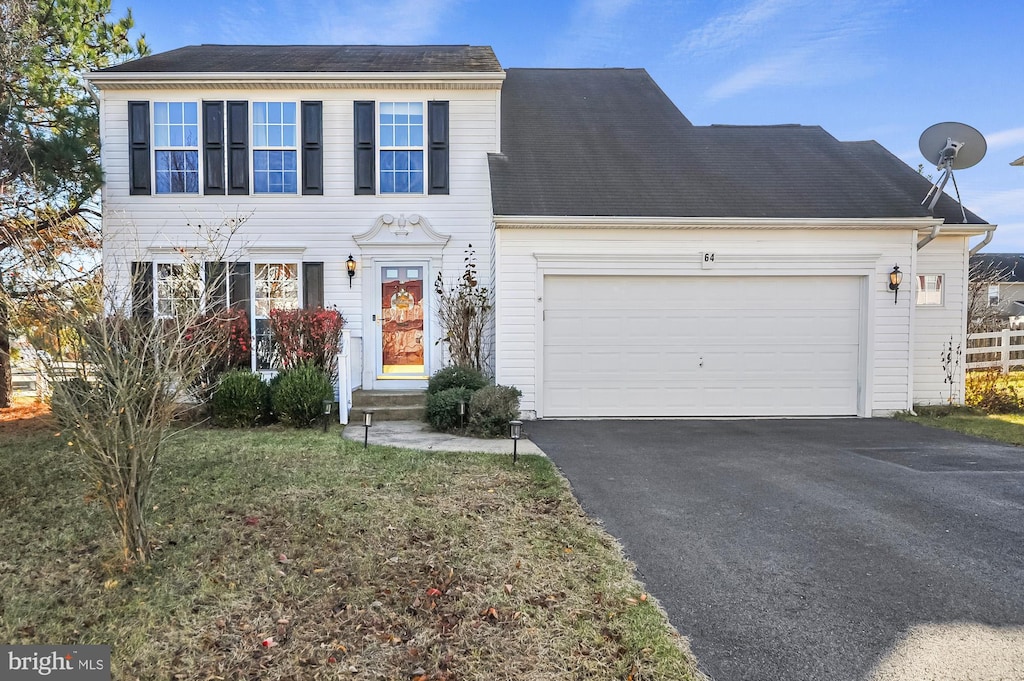 colonial home featuring a garage and a front lawn