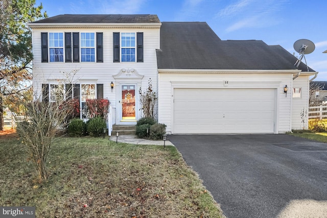 colonial home featuring a garage and a front lawn