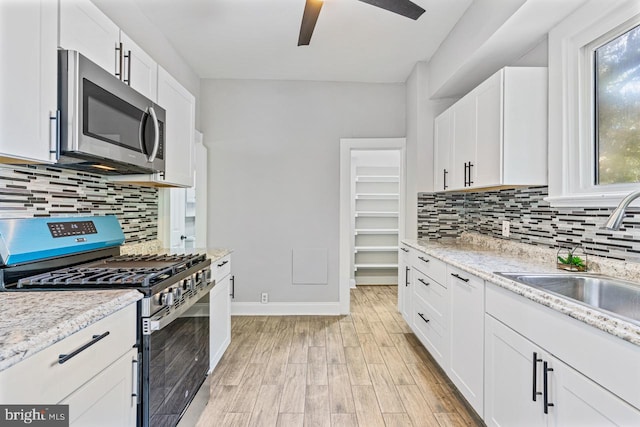 kitchen with white cabinetry, sink, stainless steel appliances, light hardwood / wood-style flooring, and backsplash