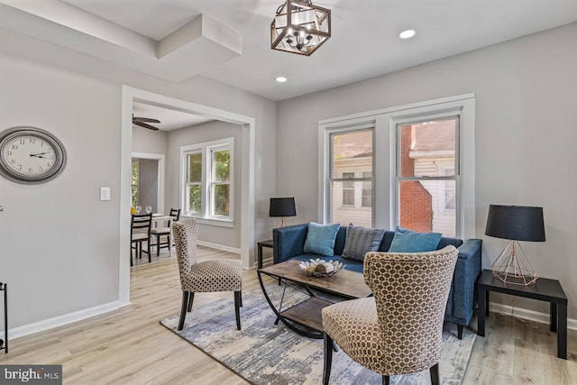 living room with light hardwood / wood-style flooring, a healthy amount of sunlight, and a notable chandelier