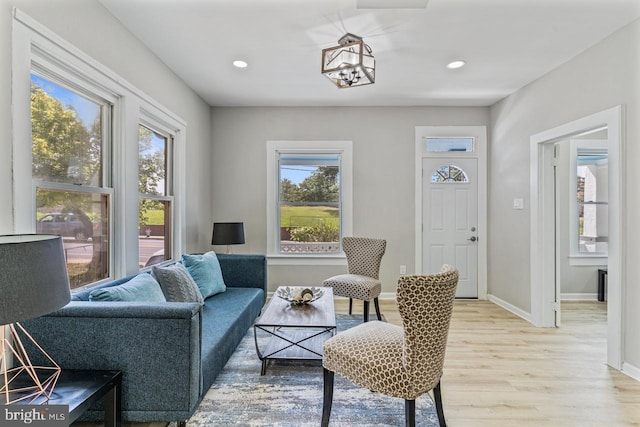 living room with a chandelier, light hardwood / wood-style floors, and plenty of natural light