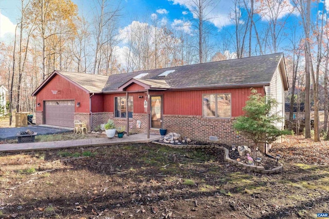 ranch-style home with brick siding, an attached garage, a shingled roof, and aphalt driveway