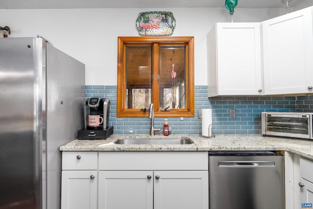 kitchen featuring light stone counters, white cabinetry, sink, and appliances with stainless steel finishes