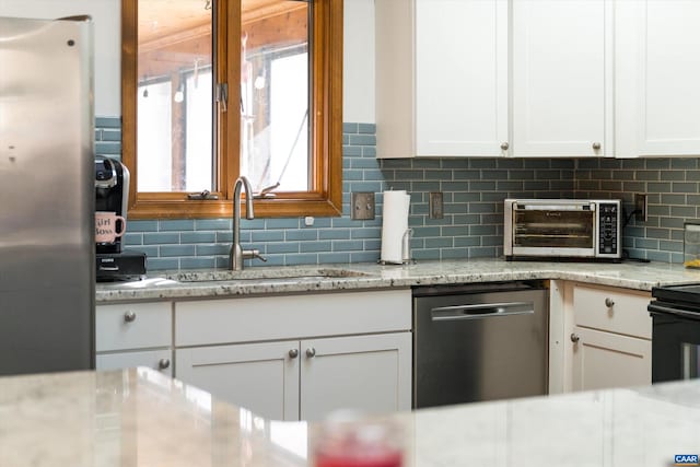 kitchen with white cabinetry, sink, stainless steel appliances, and light stone counters