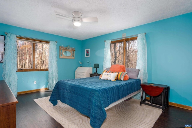 bedroom with ceiling fan, dark hardwood / wood-style flooring, and a textured ceiling