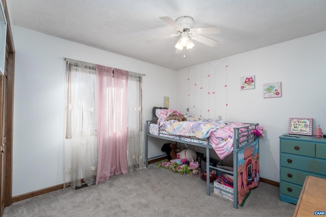 carpeted bedroom with ceiling fan and a textured ceiling