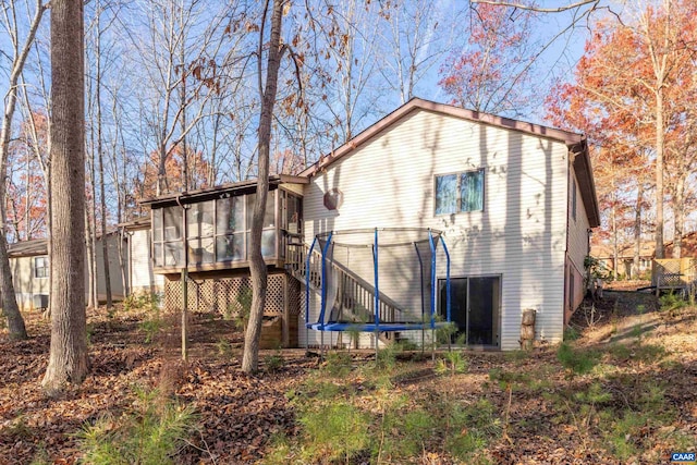 back of house with a trampoline and a sunroom