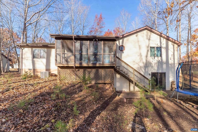 rear view of house featuring a sunroom, central AC unit, and a trampoline