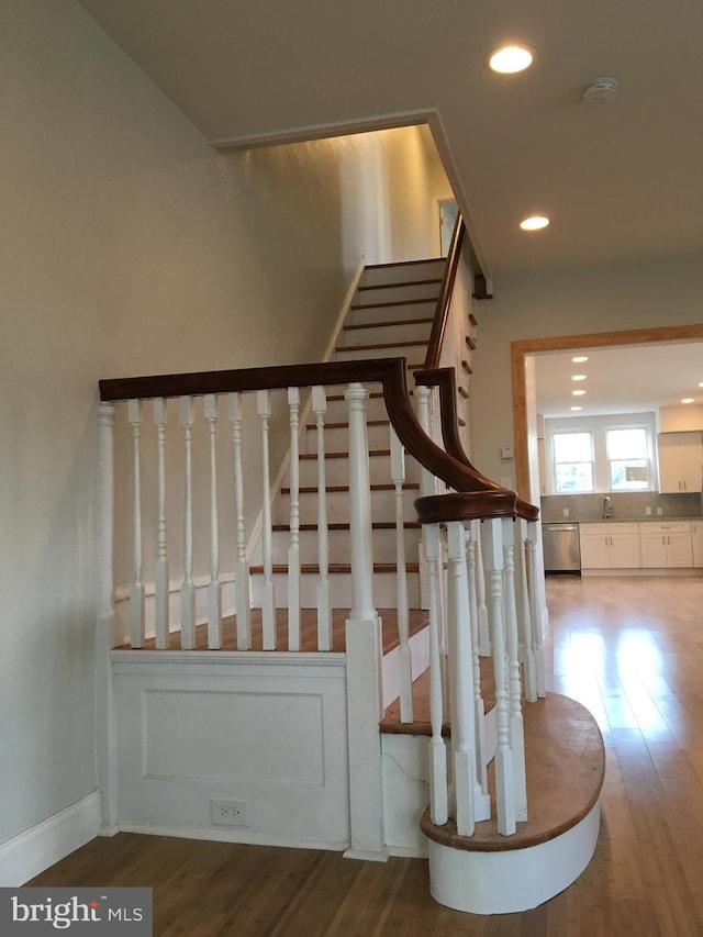 stairway with sink and hardwood / wood-style flooring