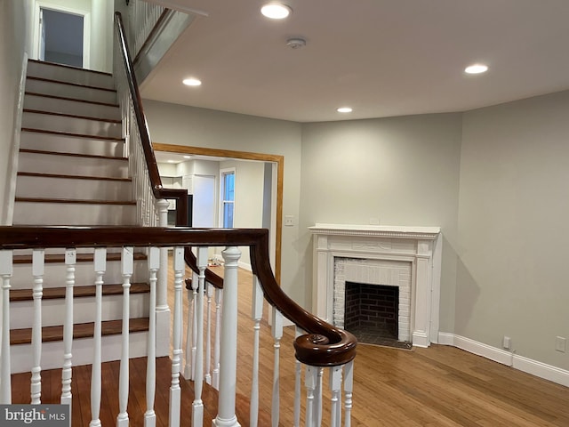 staircase with hardwood / wood-style flooring and a fireplace